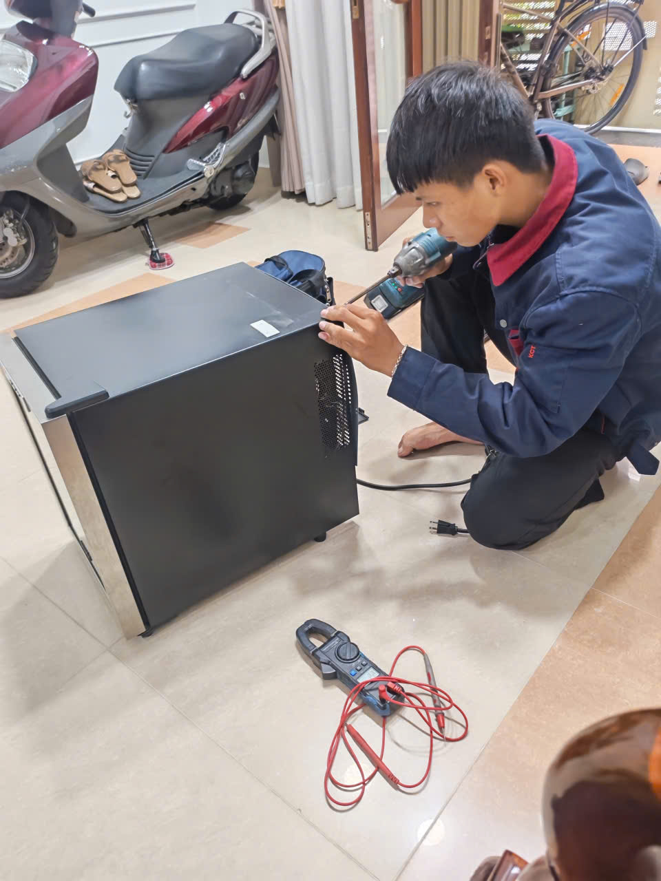Kỹ thuật viên kiểm tra vỏ và nguồn điện lò vi sóng tại nhà